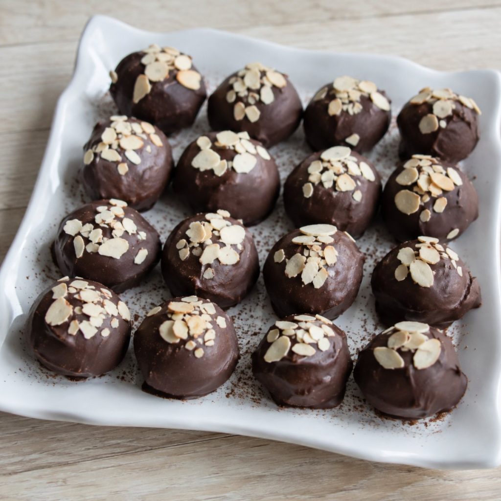 Handgemaakte marsepeintruffels met pure chocolade en amandelschaafsel, op een wit bord