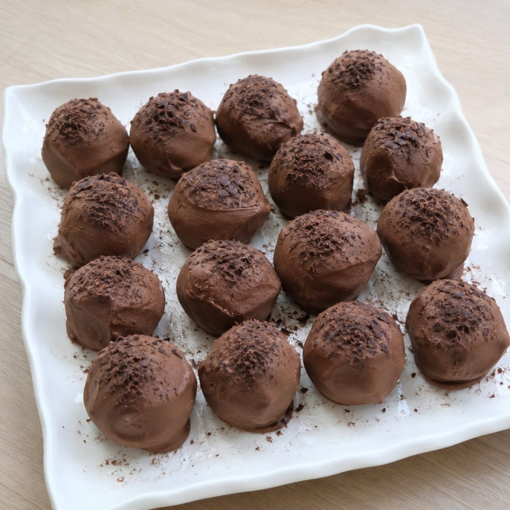Handgemaakte mokkatruffels met melkchocolade en pure chocoladeflakes, op een wit bord