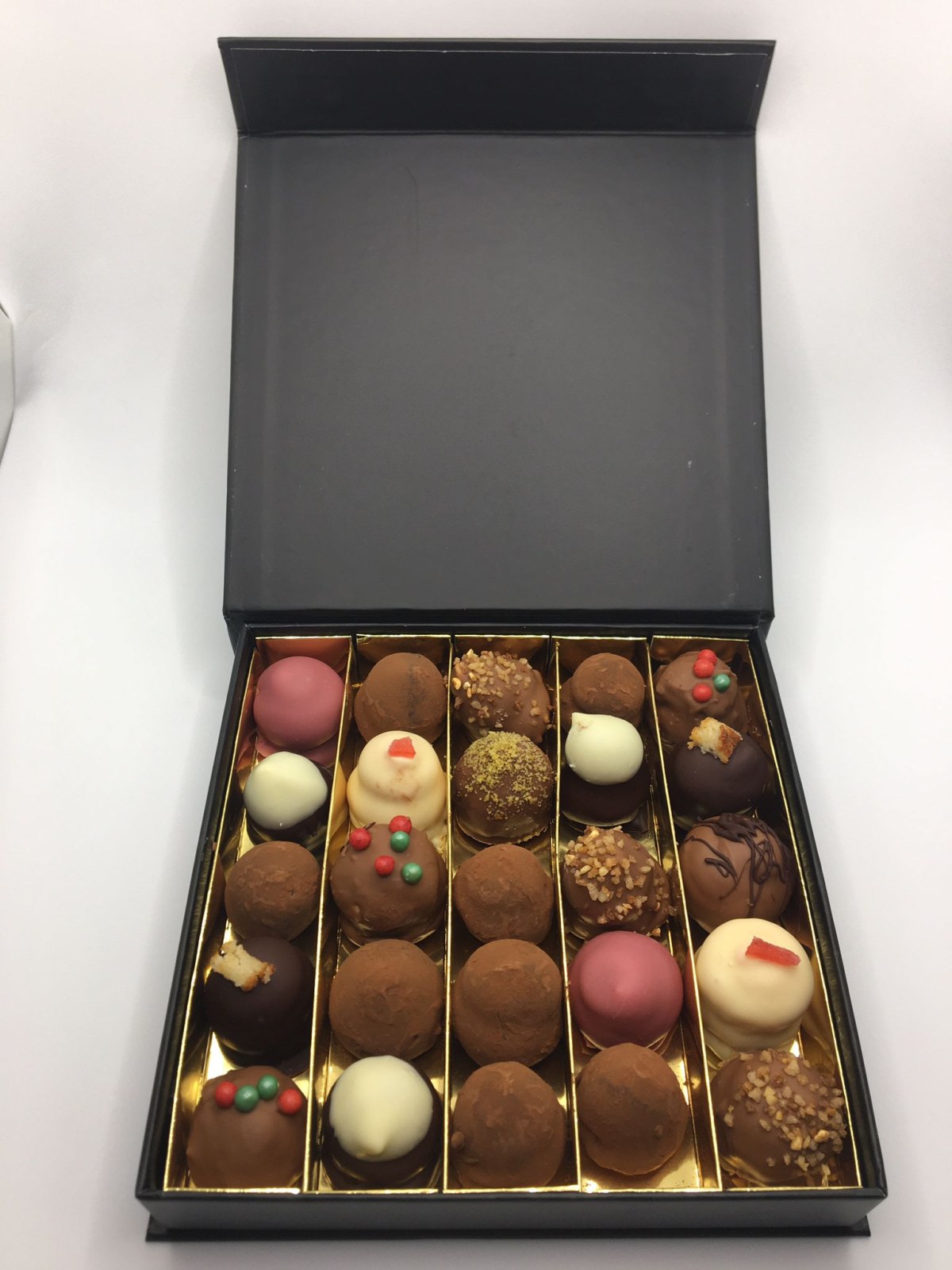 Zwarte geschenkdoos met vijfentwintig truffels, met kerstversiering